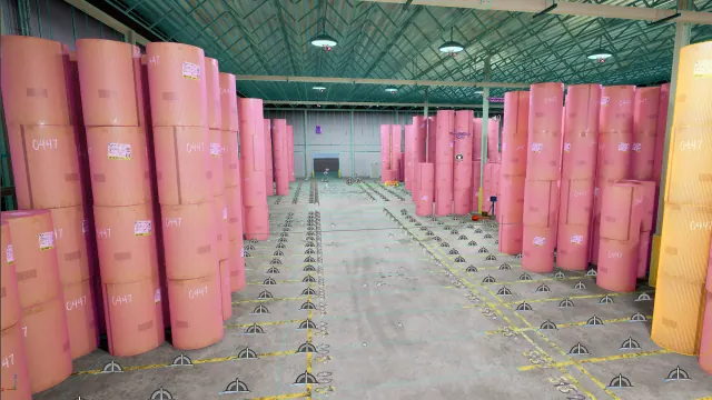Rendered warehouse aisle lined with tall stacks of pink-wrapped paper rolls under a steel roof